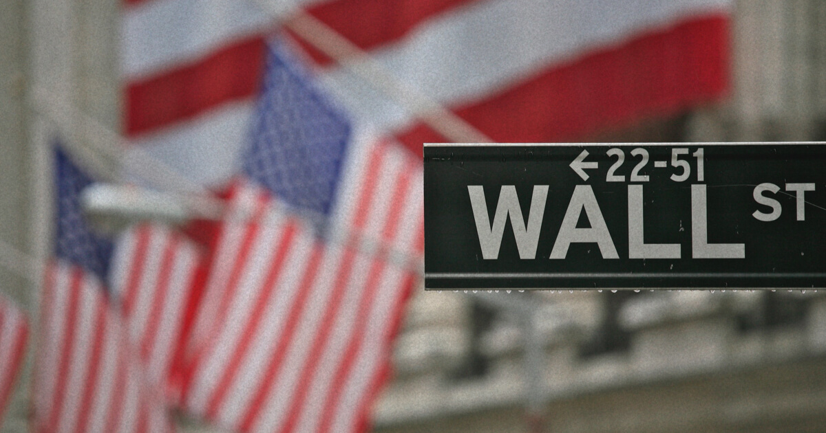 Wall Street sign with USA flags in background.